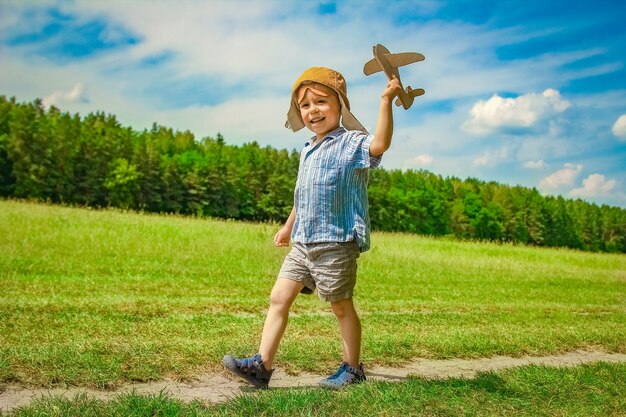 Un bébé garçon par l'avion joue sur la nature dans le parc. Garçon en vacances pilote.