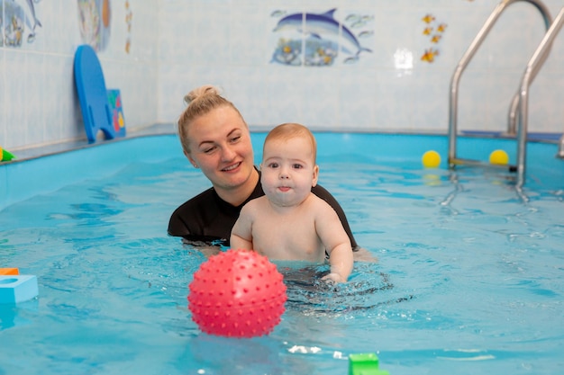 Bébé garçon s'entraîne à nager dans la piscine avec un entraîneur