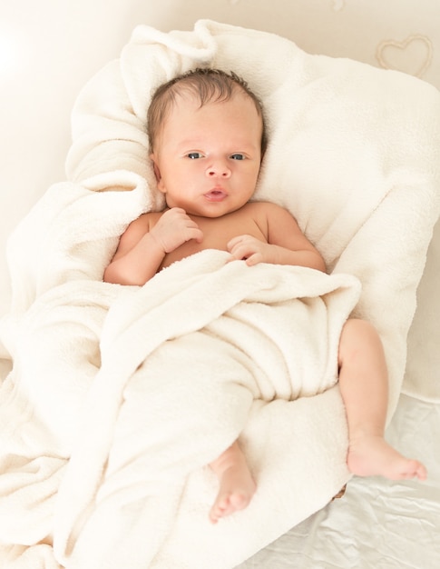 Bébé garçon avec sucette couché dans un panier en osier