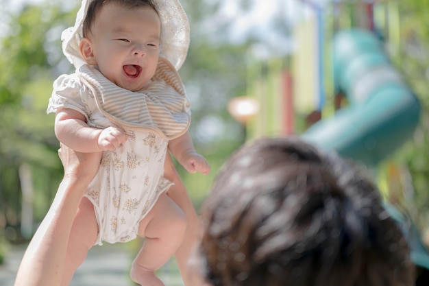 Un bébé avec un haut rayé blanc et beige est retenu par une femme.