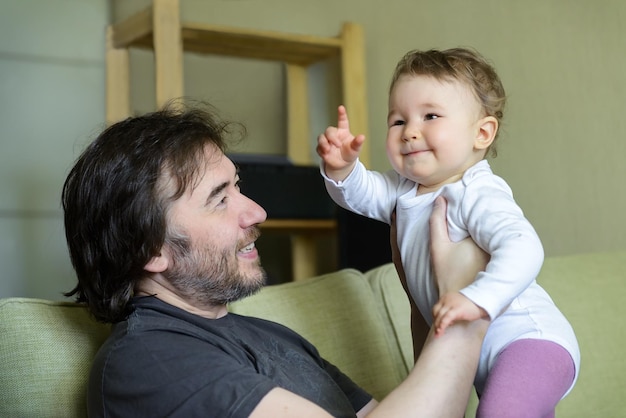 Un bébé heureux joue avec son père à la maison