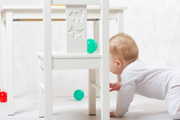 Un bébé de huit mois fait des activités sur fond gris.