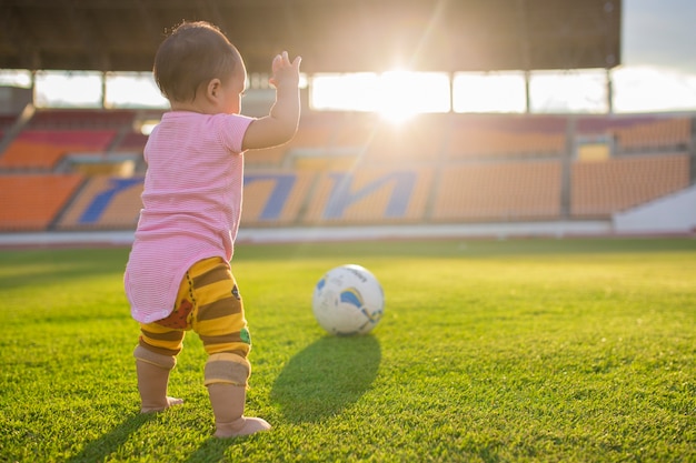 Bébé jouant footbal ou Soccerl dans le stade avec coucher de soleil