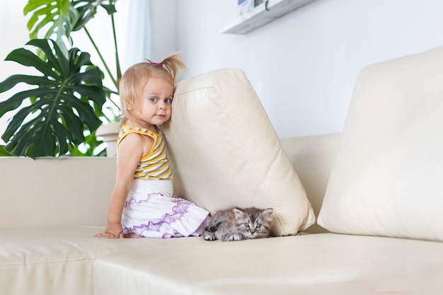 Bébé jouant avec un petit chaton sur le canapé