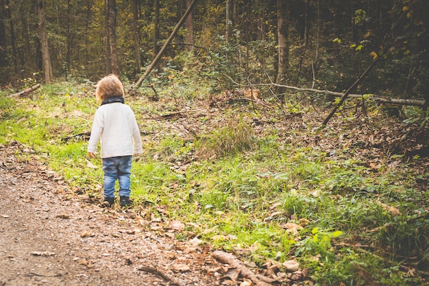 Bébé jouant sur un sentier forestier en automne