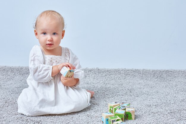 Bébé joue avec des cubes en bois sur fond clair avec copyspace. Éducation et développement des enfants.