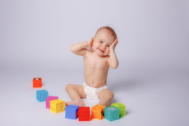 Le bébé joue avec des cubes colorés dans une couche sur fond blanc