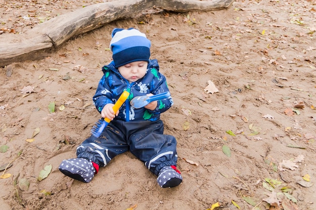 Bébé joue dans le sable en automne