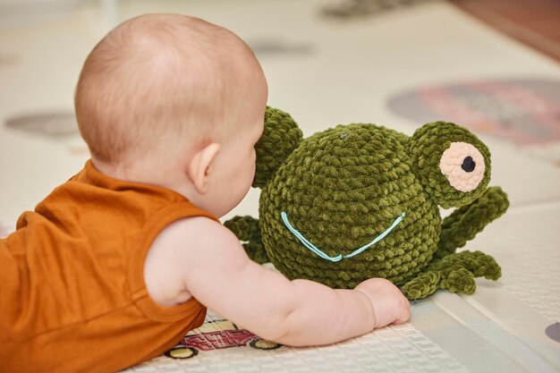 Photo le bébé joue avec un jouet tricoté dans la chambre des enfants.