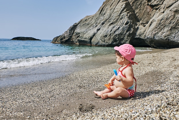 Un bébé joue avec des jouets de plage dans le sable