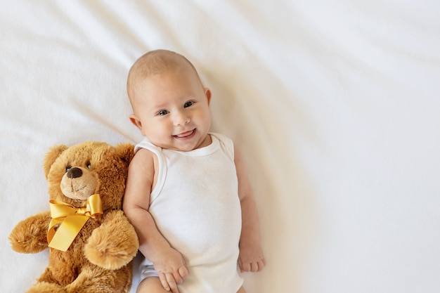 Bébé joue avec l'ours en peluche sur fond blanc.