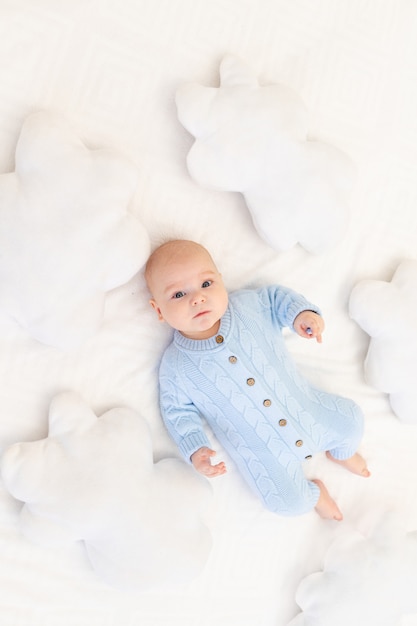 Bébé sur le lit parmi les oreillers de nuages. Textiles et literie pour enfants.