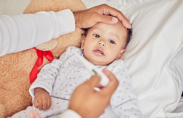 Bébé malade de covid et de fièvre avec un thermomètre d'un parent d'un enfant malade dans le lit de la chambre de leur maison Front de la main et soins de santé avec un enfant qui ne se sent pas bien et se repose dans une maison