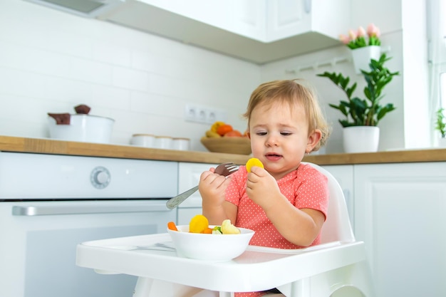 Le bébé mange des légumes sur une chaise Mise au point sélective Enfant