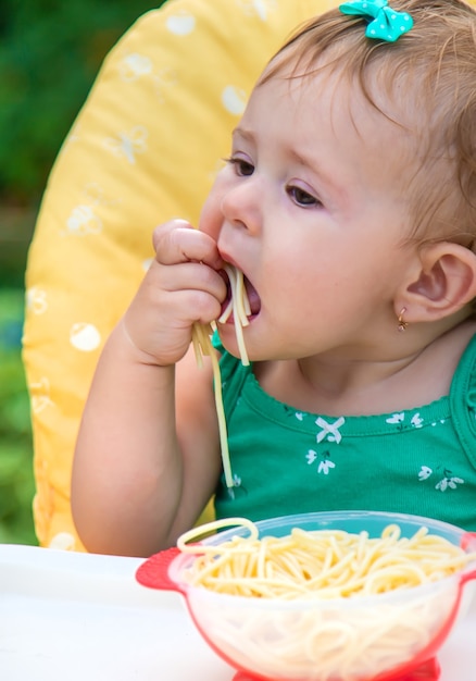 Bébé mange des spaghettis avec ses mains. Mise au point sélective. Enfant.