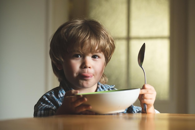 Bébé mangeant de la nourriture dans la cuisine Mignon enfant mange Rire mignon enfant bébé garçon assis dans une chaise haute et mangeant sur fond flou