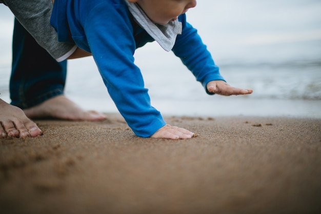 Bébé marchant avec ses mains sur le sable