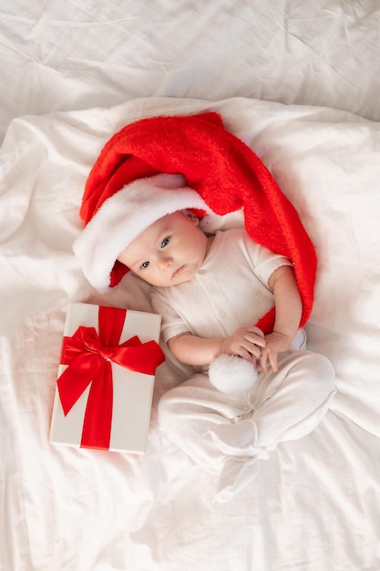 bébé mignon en bonnet de noel à la maison au lit. Le premier nouvel an. Cadeau de Noël