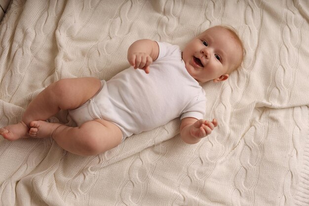 bébé mignon dans un body blanc allongé sur un couvre-lit blanc