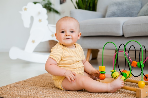 bébé mignon dans un body jaune joue avec un jouet éducatif