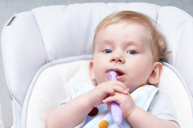 Bébé mignon dans un siège enfant mange de la bouillie. Premier leurre se bouchent