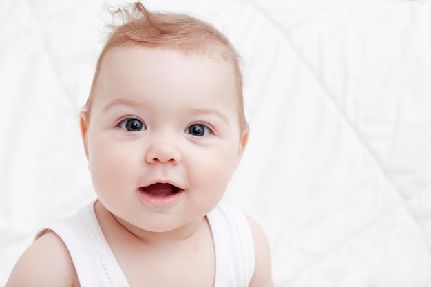 Bébé mignon avec de grands yeux et un sourire sur fond blanc. Espace copie