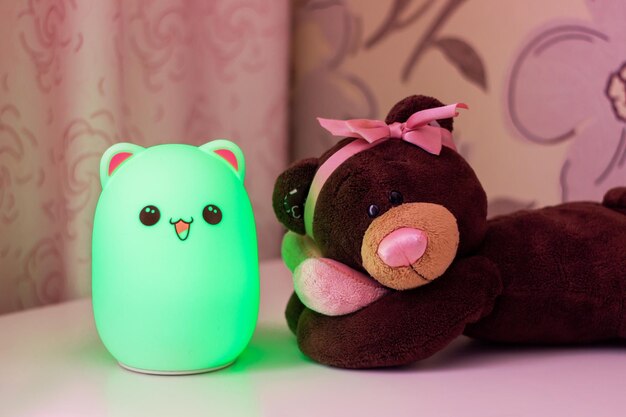 Bébé Mignon Lampe De Nuit En Forme D'ours Vert Avec Des Yeux Et Des Oreilles Près De L'ours En Peluche Dans La Chambre De Bébé Fille