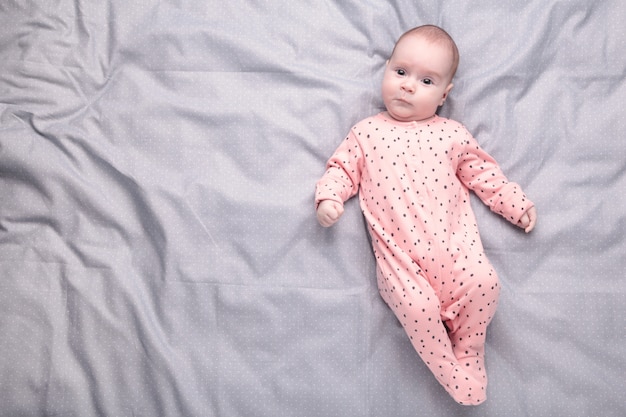 Bébé mignon sur le lit gris. Concept de bébé