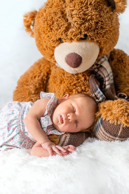 Photo un bébé mignon avec un ours en peluche qui dort sur le lit à la maison.