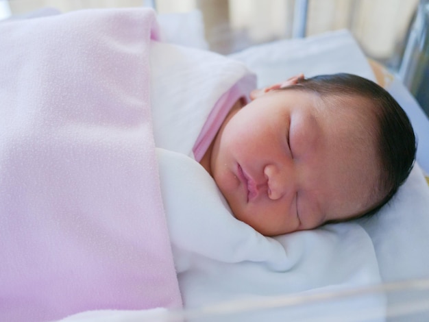 Un bébé mignon qui dort sur le lit.