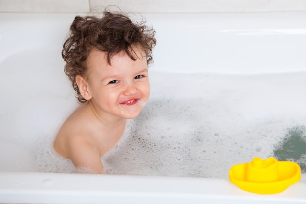 Bébé mignon se lave dans le bain. Le symbole de la pureté et de l'éducation à l'hygiène.