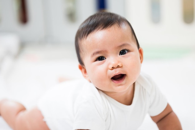 Un bébé mignon vêtu d'une robe blanche Reste avec les parents dans la maison