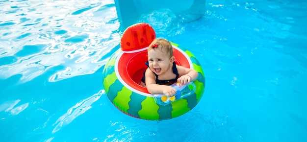 Bébé nage en cercle dans la piscine. Mise au point sélective.