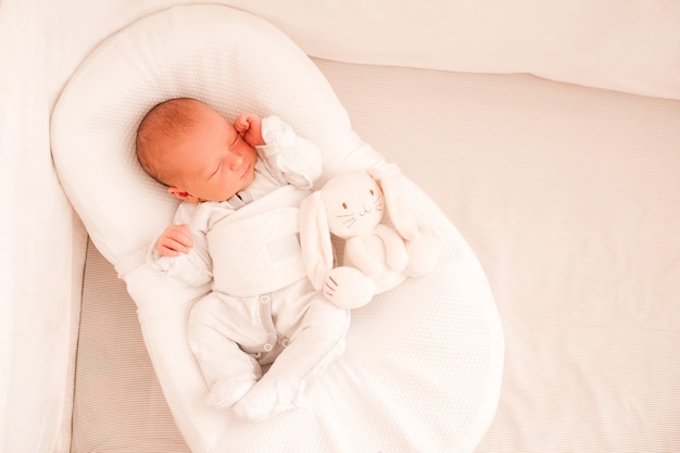 Bébé nourrisson dormant dans un cocon portant un pyjama au lit