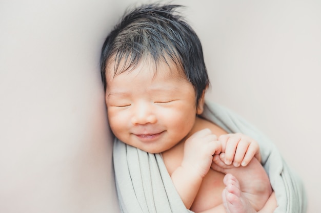 Bébé nouveau-né asiatique dormir dans une couverture sur le lit