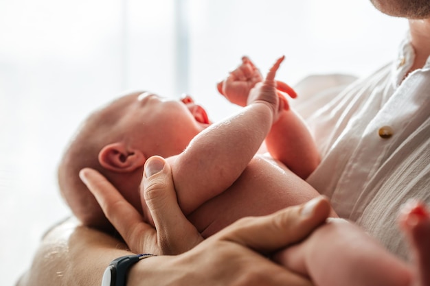 Bébé nouveau-né dans les bras de papa à la maison attention aux détails gros plan Le concept de soins et d'amour