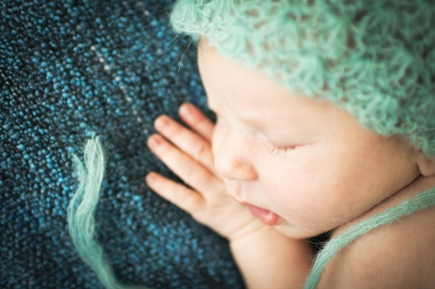 Bébé nouveau-né dormant doucement sur un tapis bleu en bonnet bleu