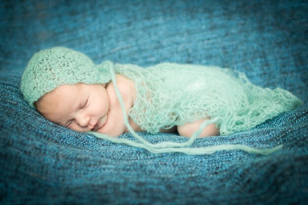 Photo bébé nouveau-né dormant doucement sur un tapis bleu en casquette bleue