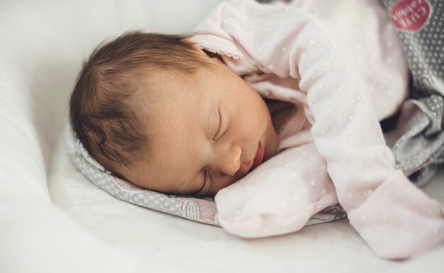 Bébé nouveau-né dort bien tout en portant des vêtements chauds et allongé sur un canapé pour bébé