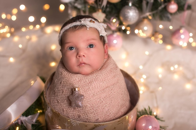 Bébé nouveau-né sur le fond des guirlandes d'arbres de Noël de Noël