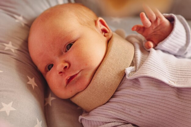 Bébé nouveau-né mignon dans un appareil orthopédique. Enfant portant un collier cervical, Traitement d'une lésion de la colonne vertébrale chez un enfant.