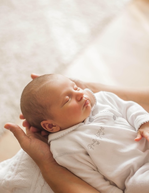 Bébé nouveau-né mignon dormant dans les bras de la mère. Maternité.