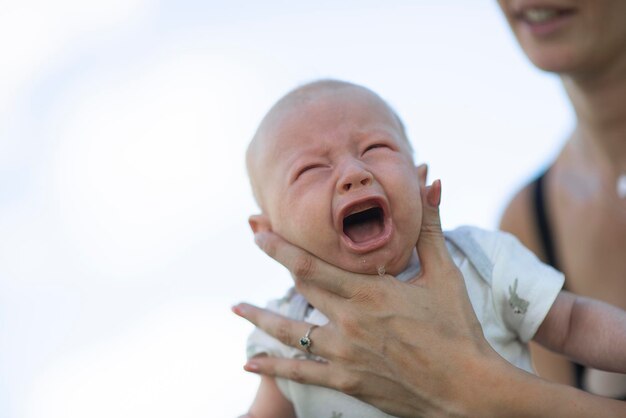 Photo bébé nouveau-né pleurant devant sa mère alors qu'elle la tient et essaie de la réconforter