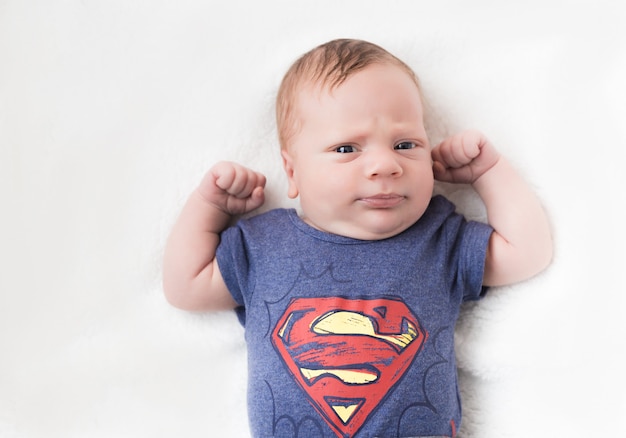 bébé nouveau-né sérieux dans un costume de super-héros sur fond blanc