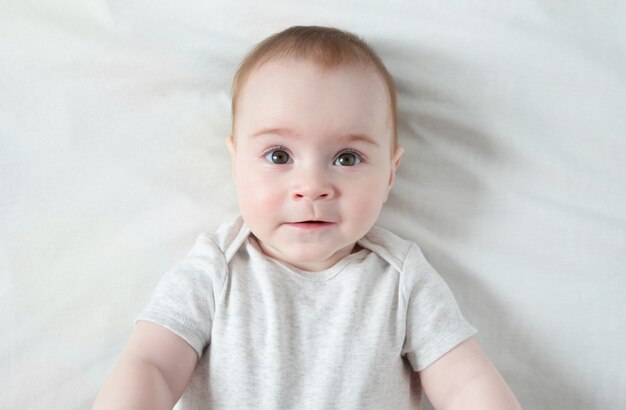 Bébé paisible allongé sur un lit blanc, vue de dessus