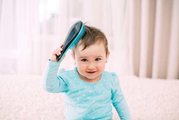 Bébé avec un peigne une petite fille avec un peigne bleu peigne ses cheveux