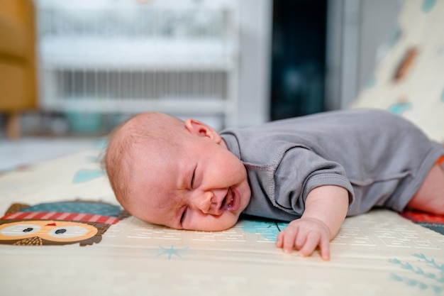 Le bébé pleure en essayant de lever la tête allongé sur le ventre