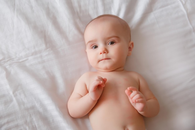 bébé porte des couches et une serviette blanche dans la chambre Un nouveau-né se repose au lit après une ba