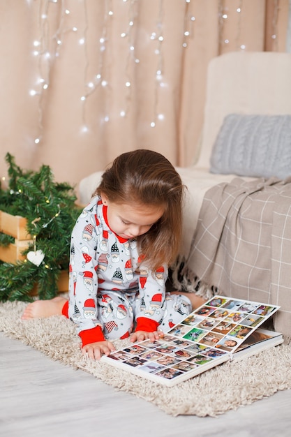 Bébé en pyjama avec le Père Noël est assis sur le sol à l'intérieur du Nouvel An à Noël