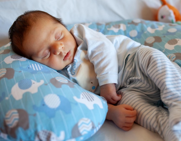 Un bébé de quelques jours dort sur un oreiller rond La phase de sommeil est très importante dans l'enfance